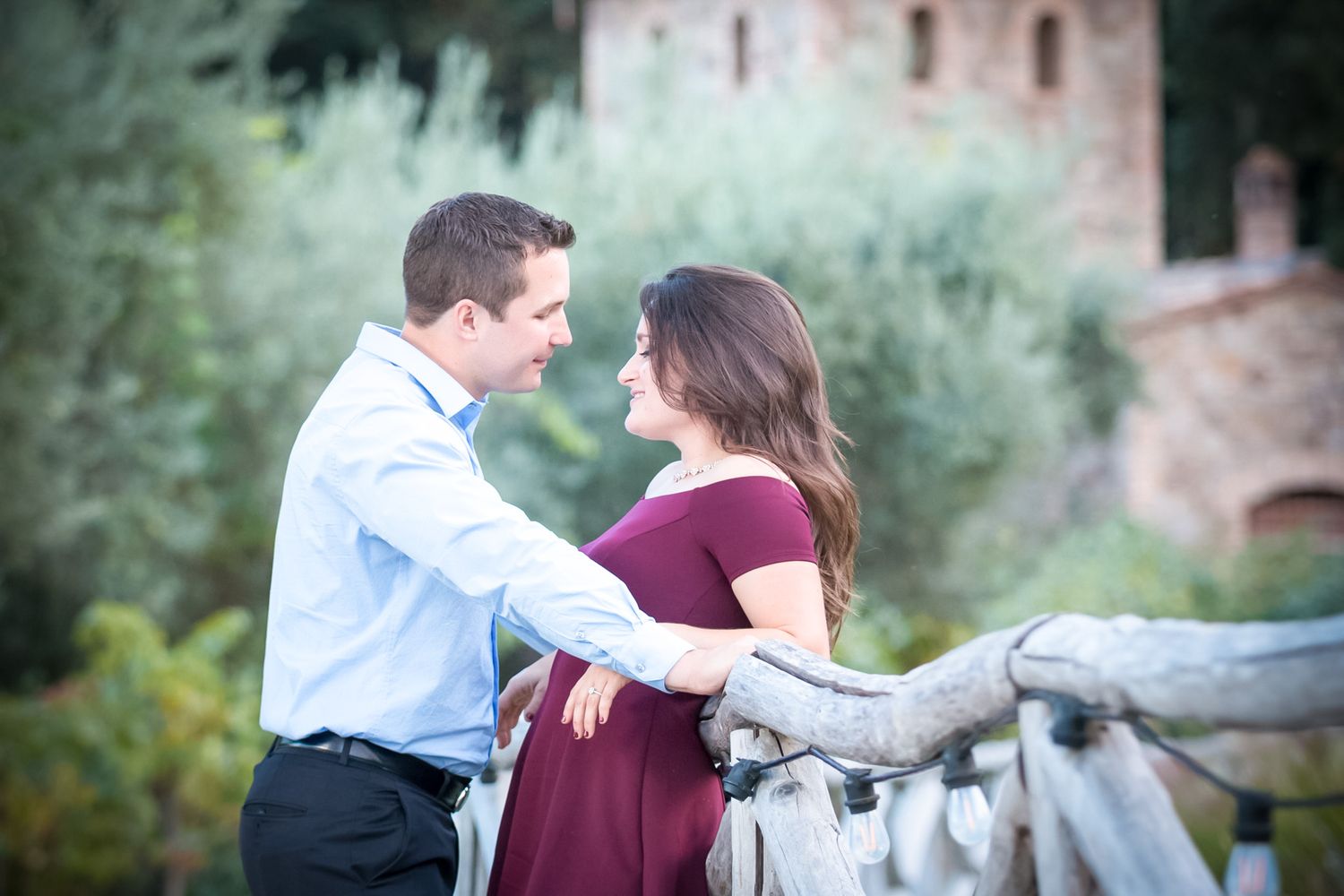 Romantic couple embrace on pathway with castle architecture in background.