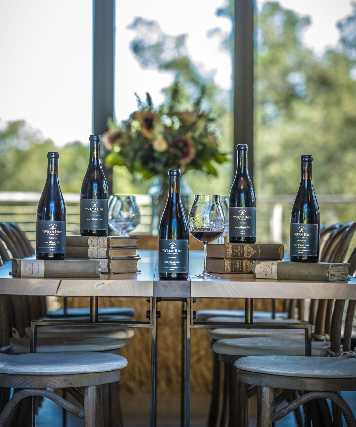 Elegant wine tasting setup with bottles and glasses arranged on wooden table with floral centerpiece.