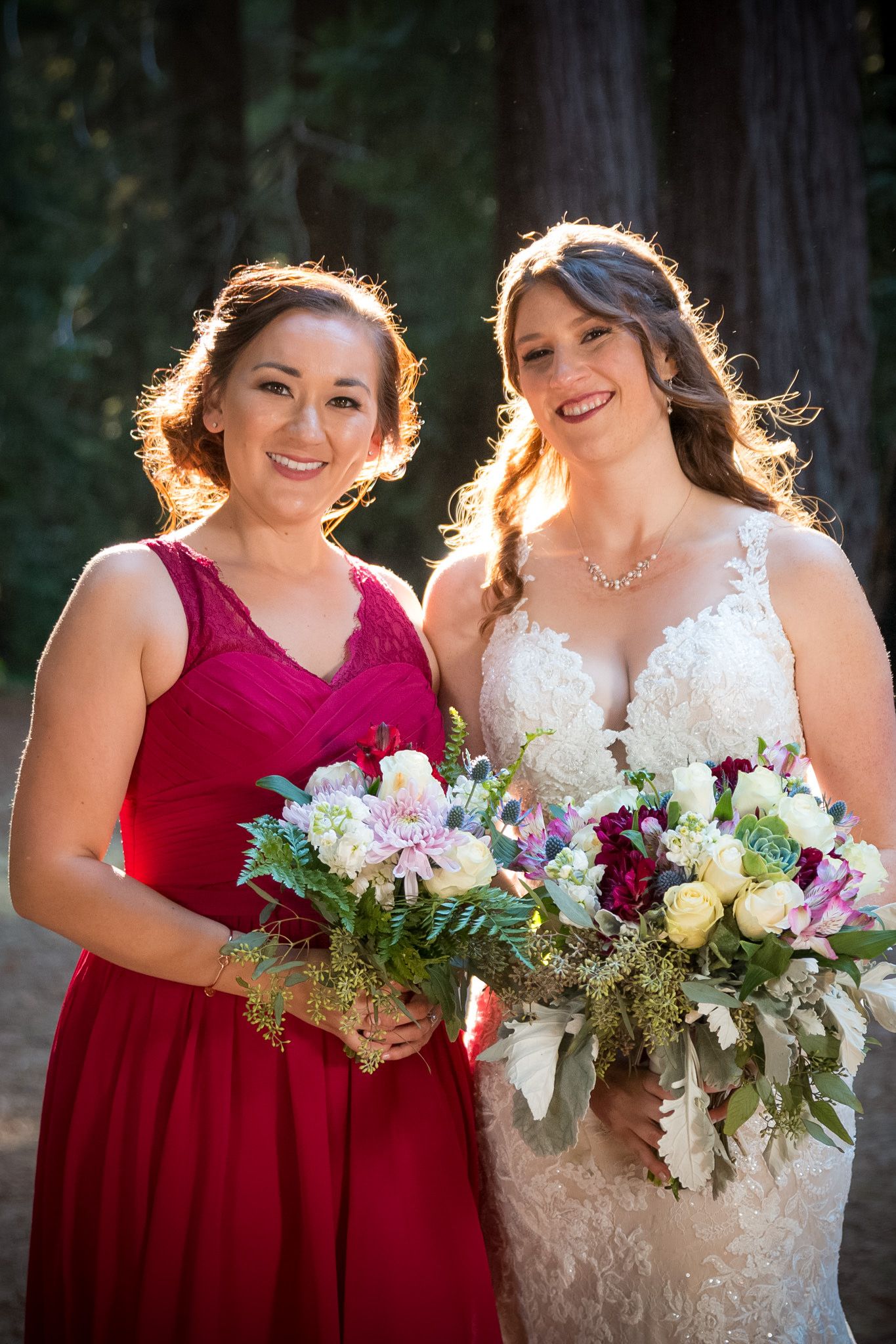 Sun-lit portrait of wedding party members with vibrant bouquets in forest.