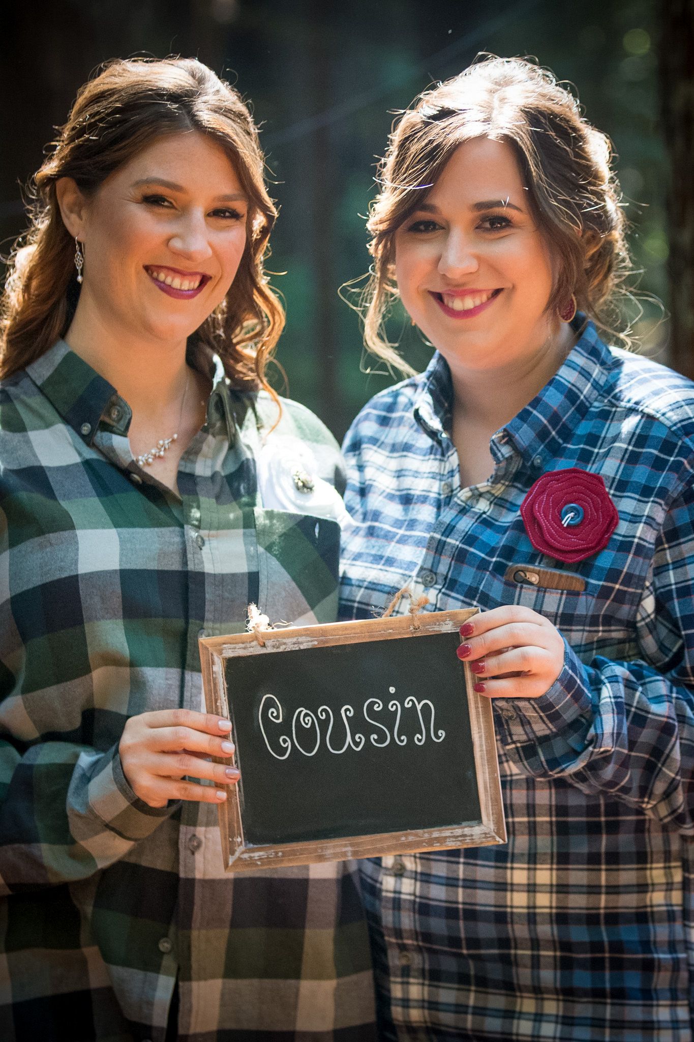 Friends holding chalkboard signs in casual plaid shirts outdoors.