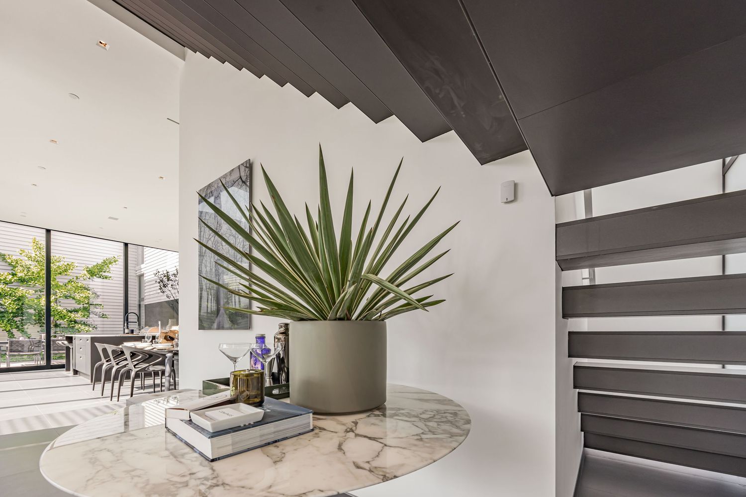 Modern interior staircase with floating steps and a large potted plant.