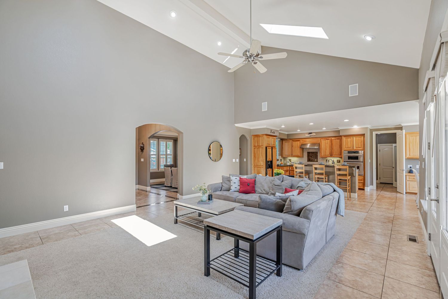 Open concept living area with vaulted ceilings, skylights, and gray sectional sofa.