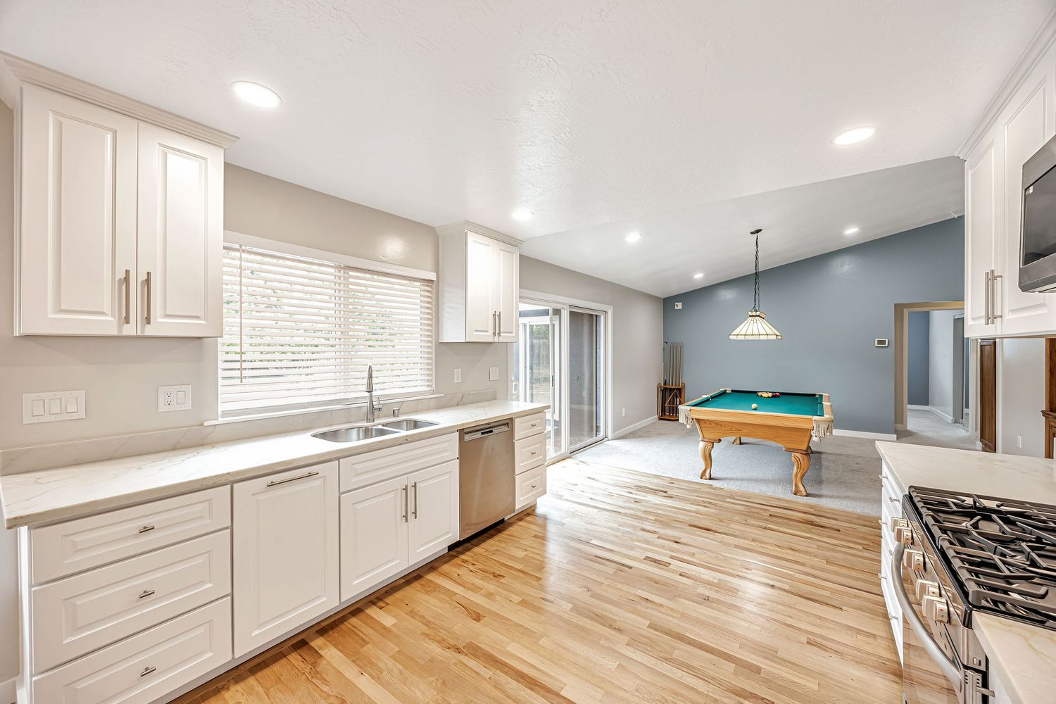 Contemporary kitchen featuring white cabinets, quartz countertops, and hardwood floors.