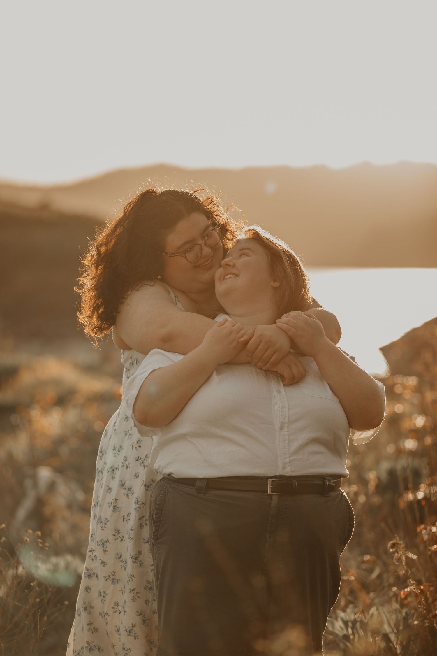 Two people embracing in a loving moment during golden hour in a field of wildflowers.
