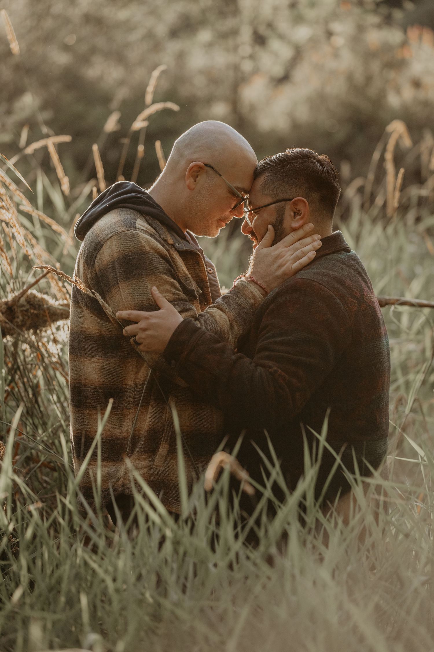 An intimate moment between two people sharing a tender embrace among tall grasses at golden hour.