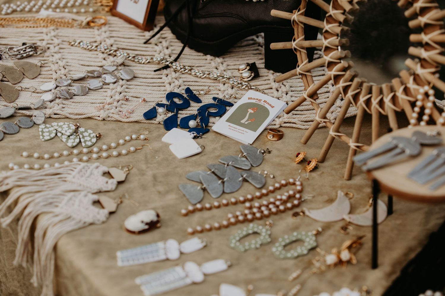 Jewelry accessories and decorative items arranged on a beige textured fabric with a circular woven element.