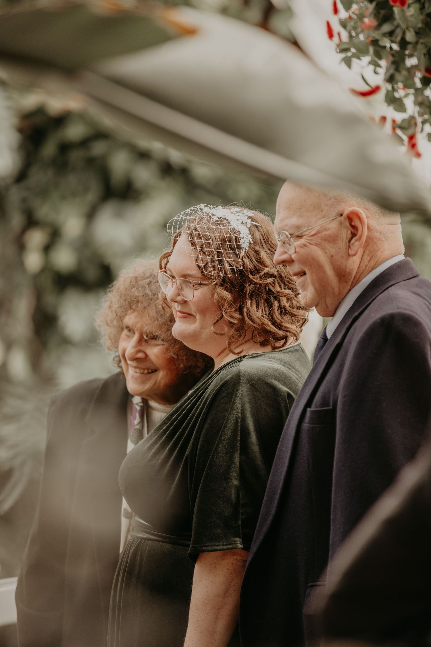 Three people standing together smiling in warm lighting at what appears to be an outdoor event or gathering.