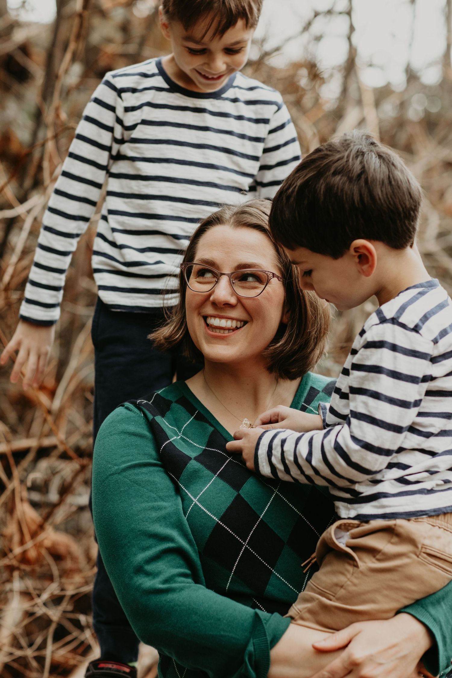 A joyful family moment captured outdoors in autumn with matching striped shirts and a green sweater.