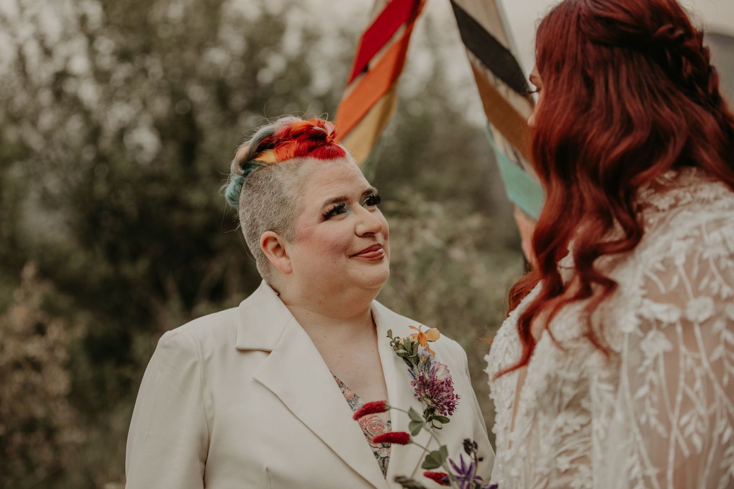 Two partners share an intimate moment on their wedding day in a natural outdoor setting.