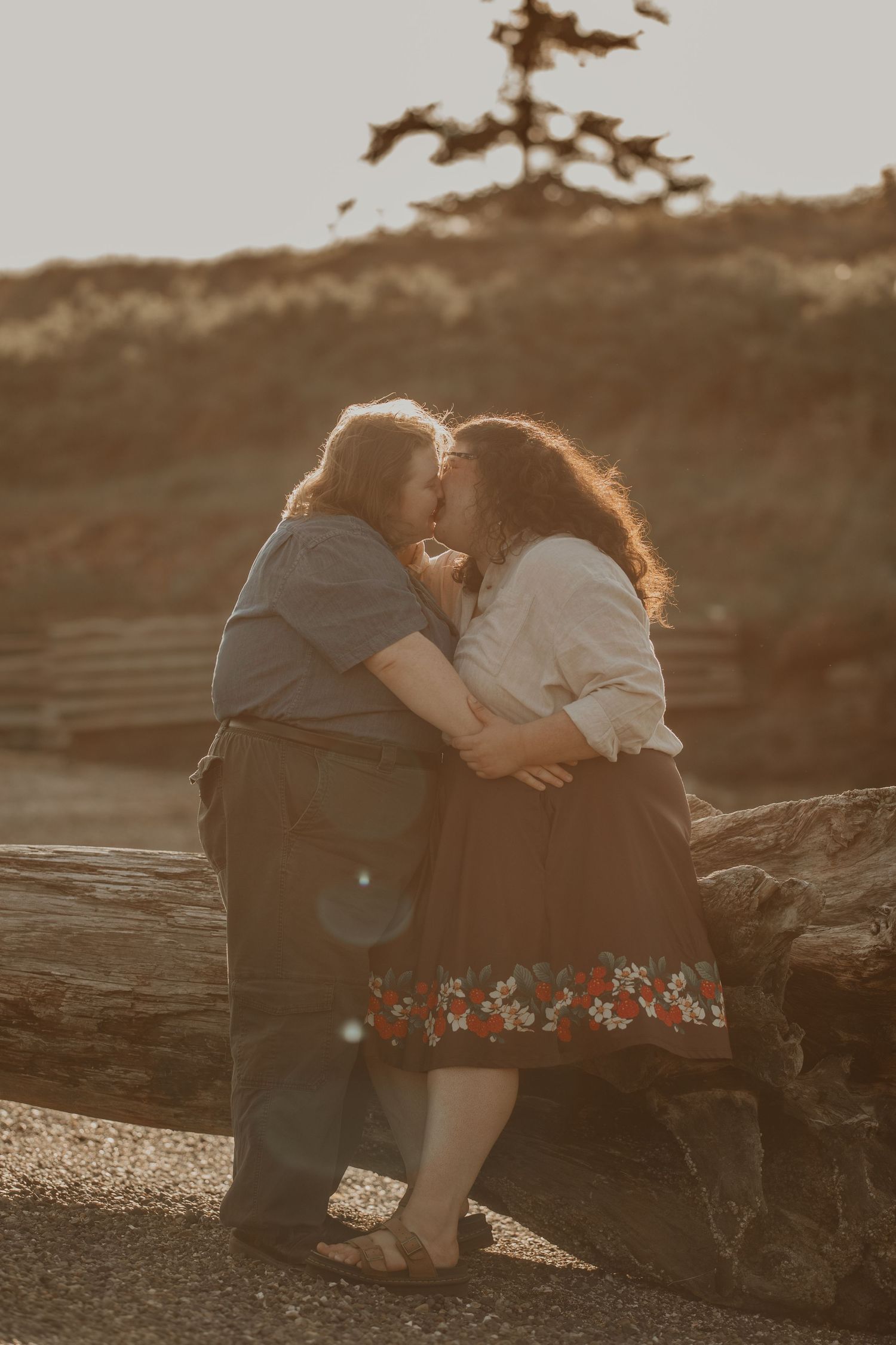 A romantic couple embraces on rocky terrain at sunset in warm sepia tones.