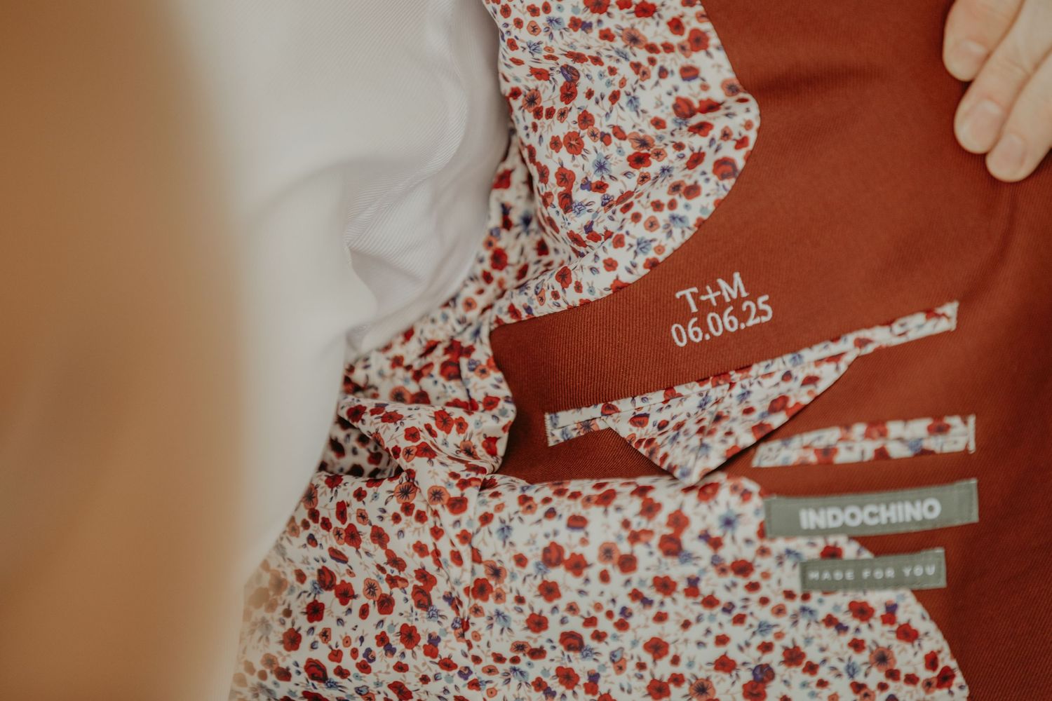A close-up view of a rust-colored garment with white floral print pattern and clothing tag details.