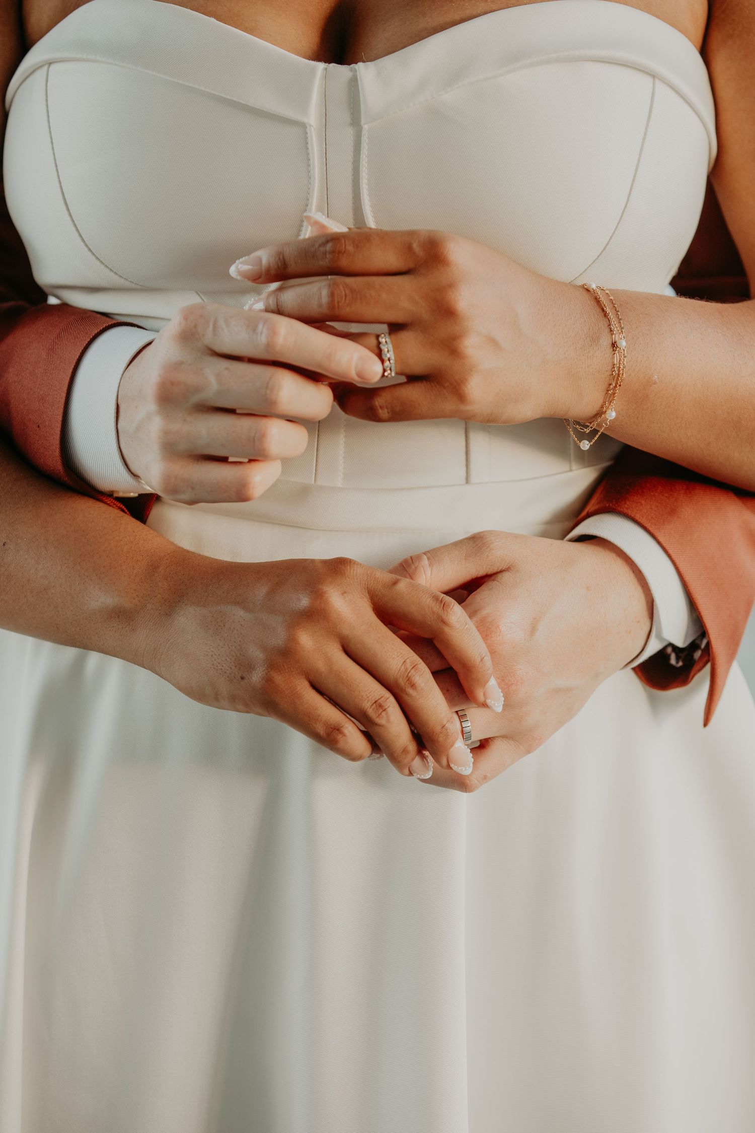 Close-up detail shots of hands with rings in white wedding attire showing elegant jewelry and fabric details.
