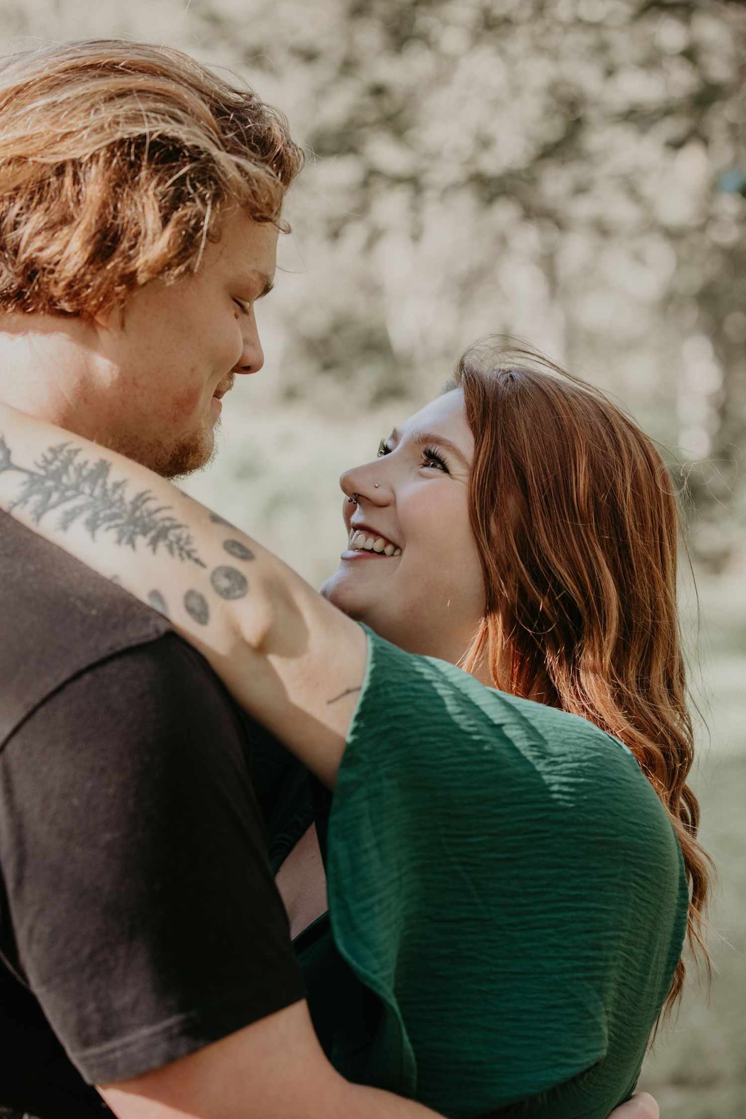 A close-up romantic moment between a couple embracing and smiling at each other outdoors.