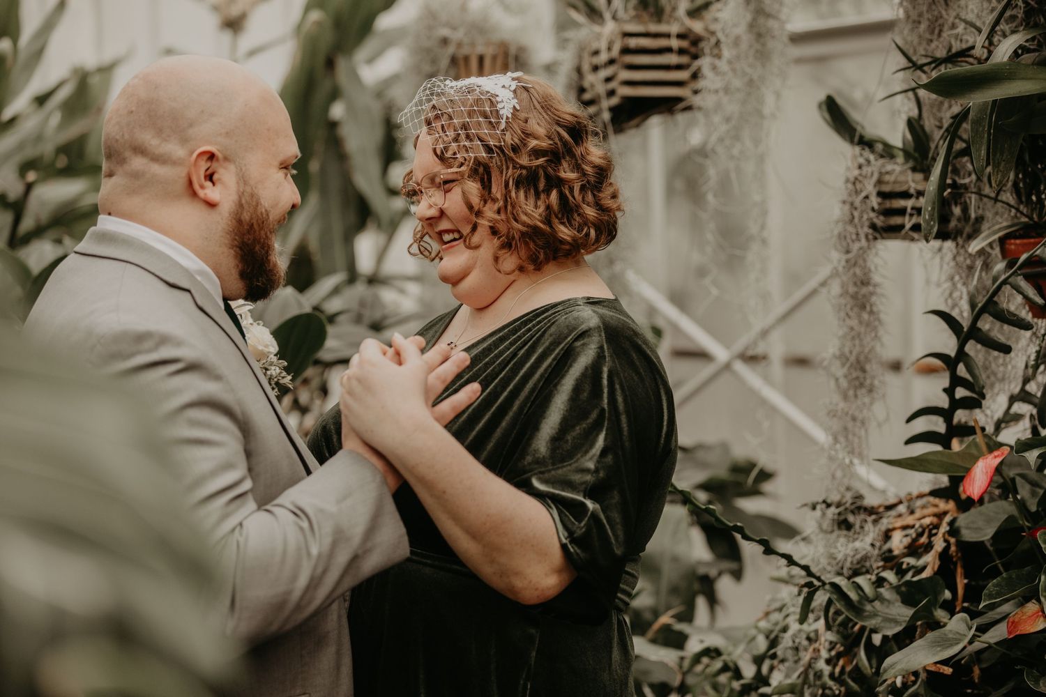 A couple shares an intimate dance moment together in front of a garden wall.