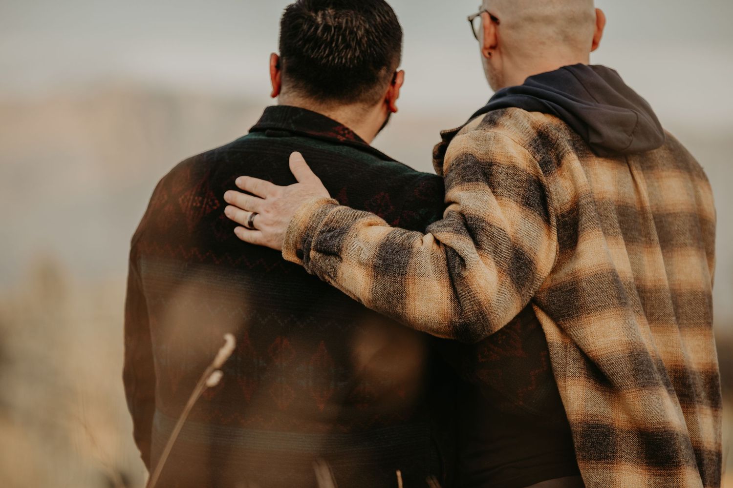 A soft romantic embrace captured in warm sunlight amidst a golden countryside setting.