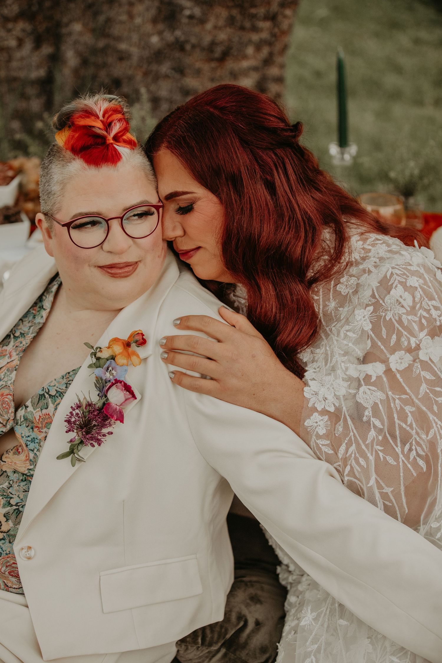 Two people in wedding attire sharing an intimate moment outdoors with floral details and a mix of vintage and modern styling.