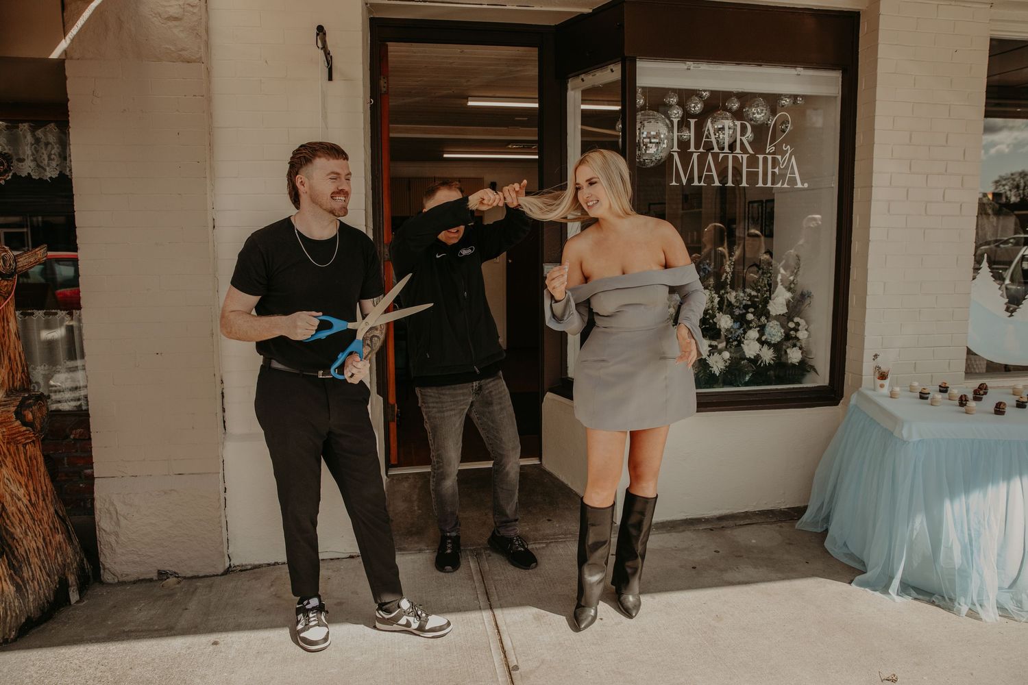A group stands outside a local storefront with light cafe tables and decorative elements visible in the scene.