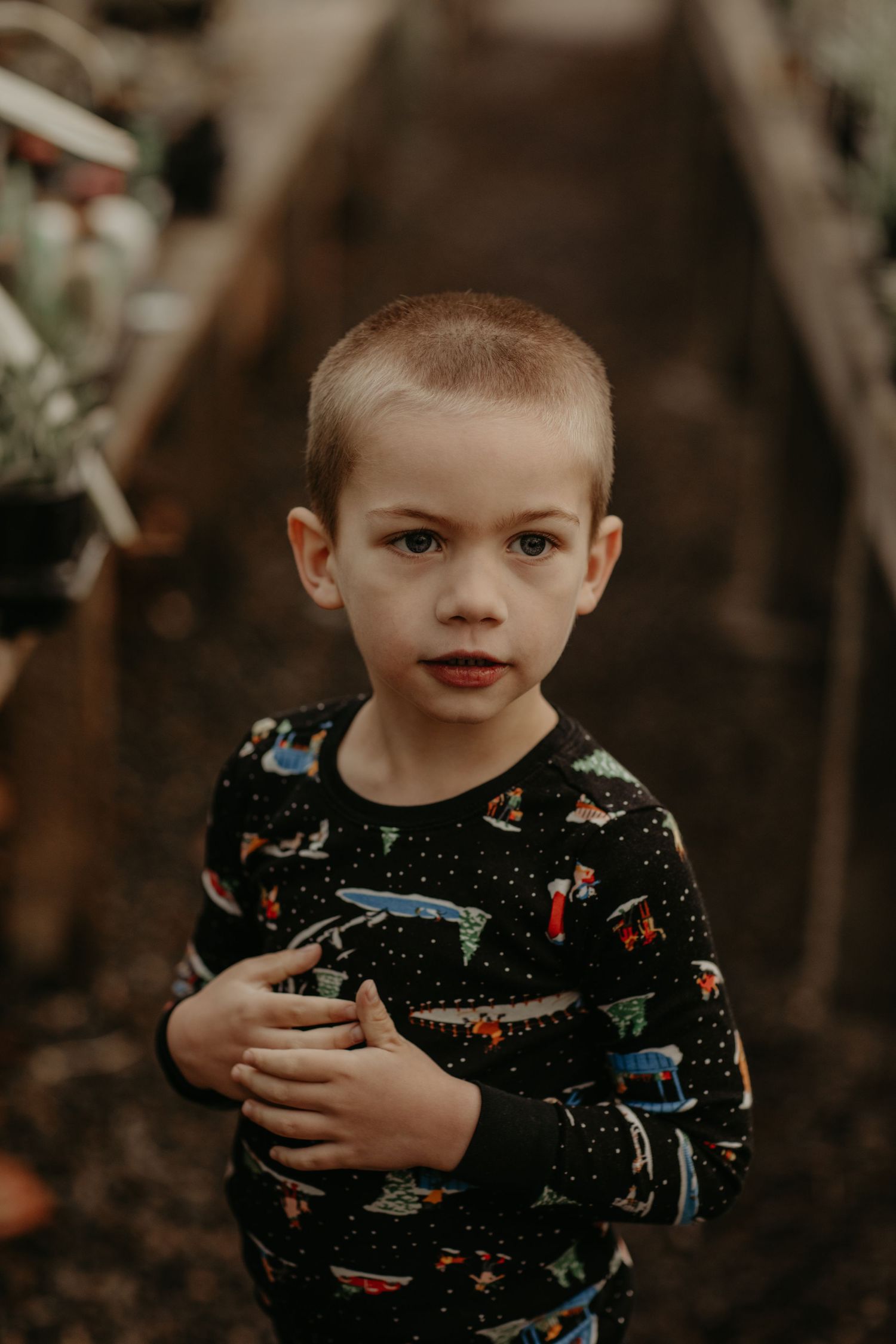 A child stands outdoors wearing a navy blue sweater with colorful space-themed print pattern.