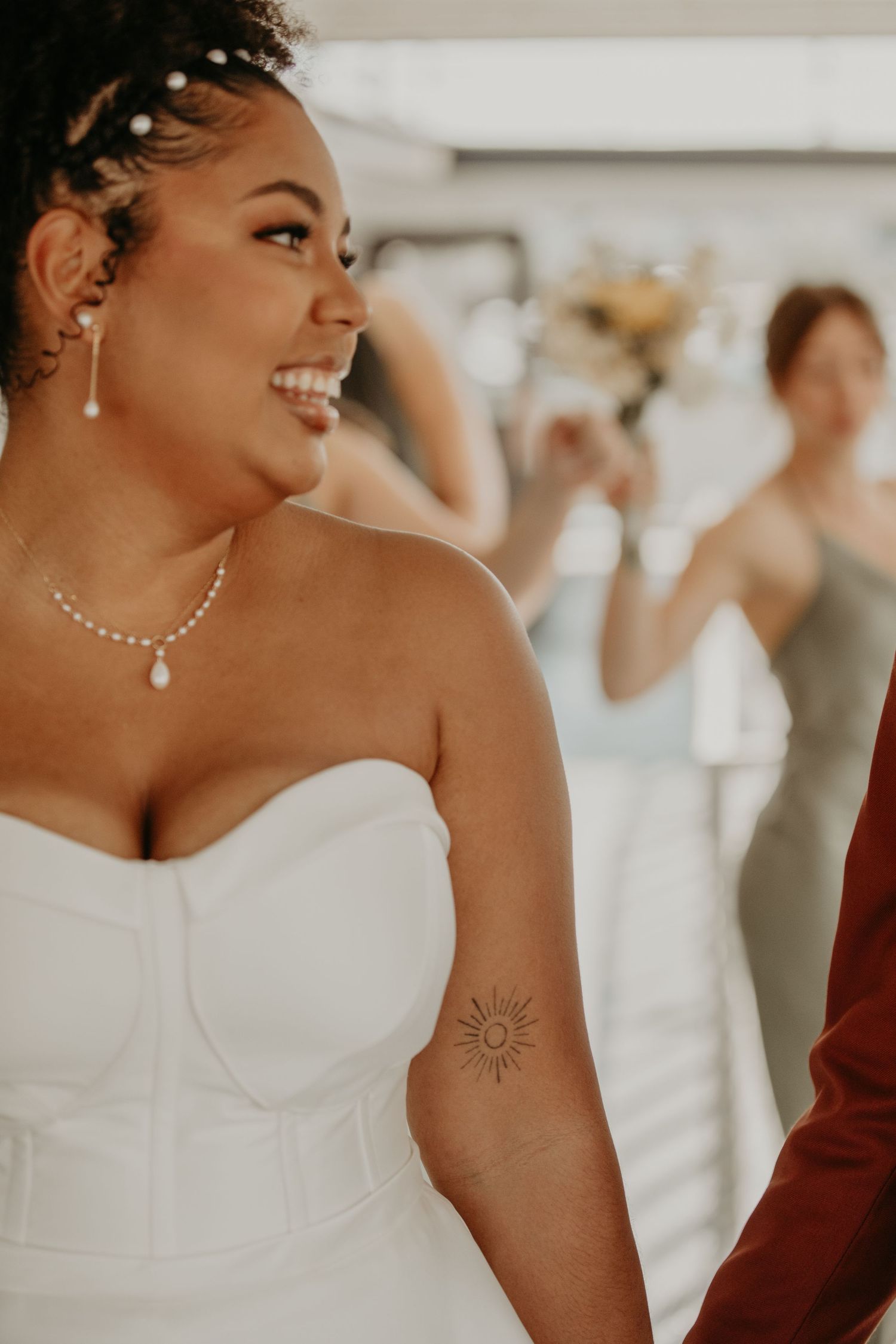 Close-up of a bride in a white strapless dress wearing a pearl necklace and delicate earrings.