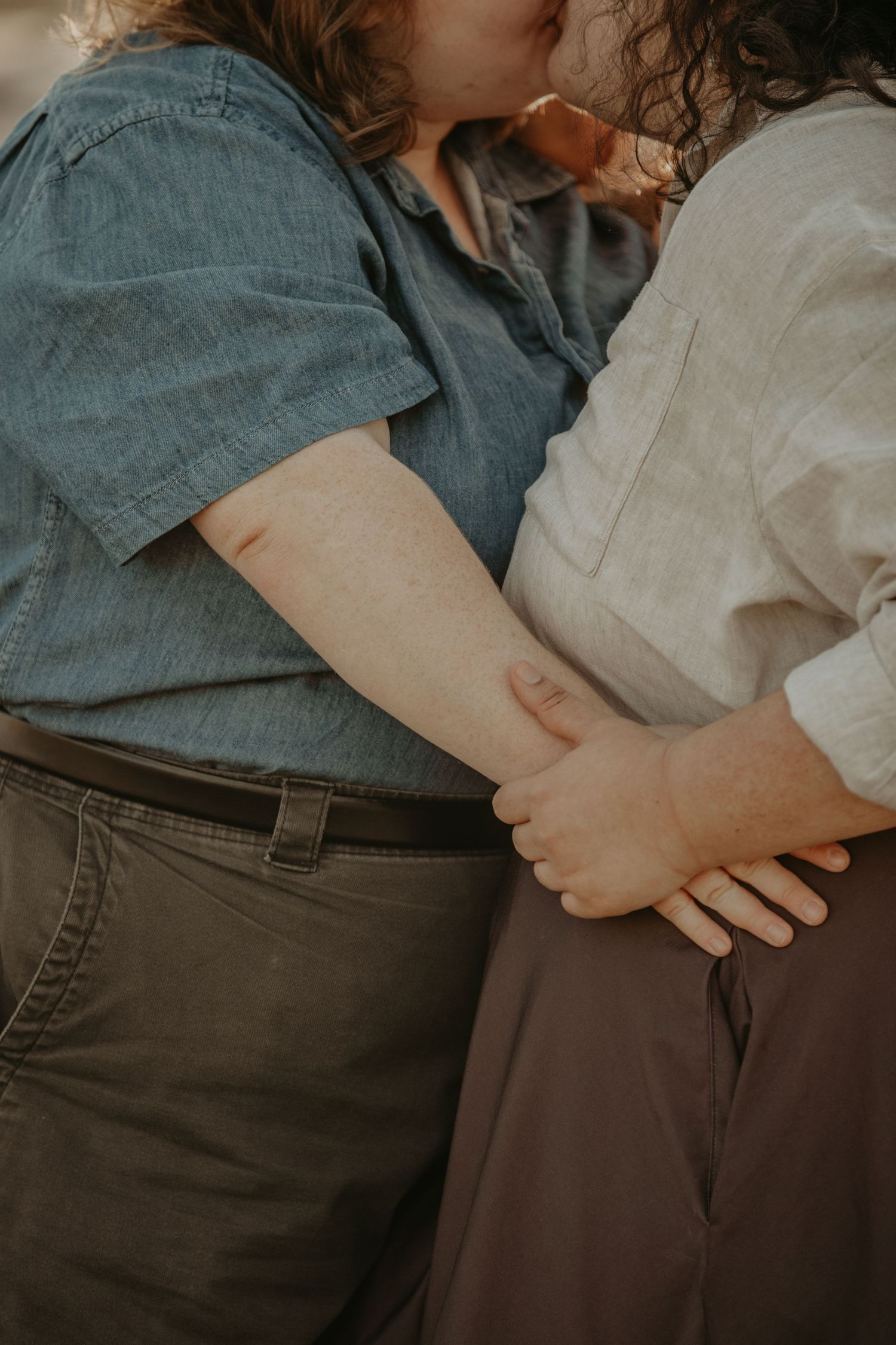 Close-up shot of two people holding hands wearing casual denim and linen clothing.