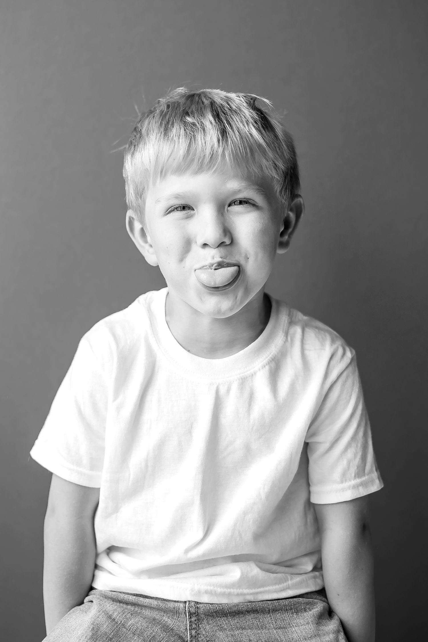 Black and white portrait of young child sticking tongue out playfully.