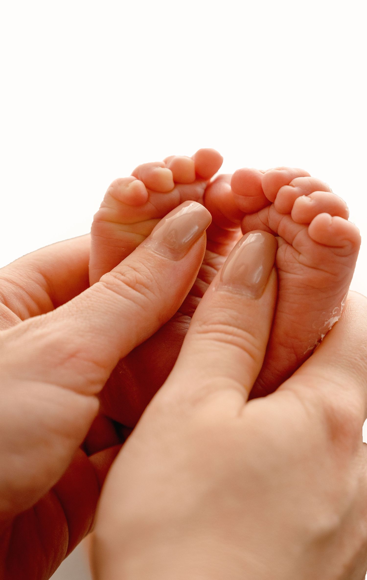 Close-up of tiny baby feet being gently held by adult hands.