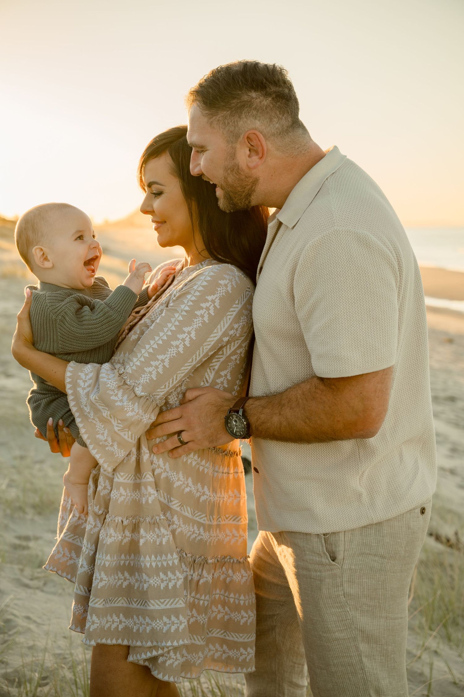 Family shares joyful moment together during sunset beach photoshoot.