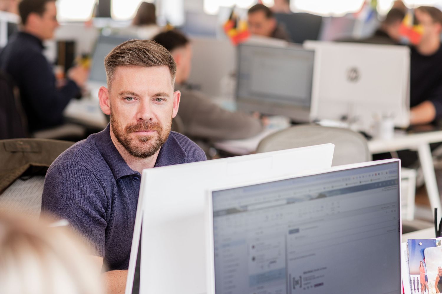 Professional working at computer in busy modern office environment.