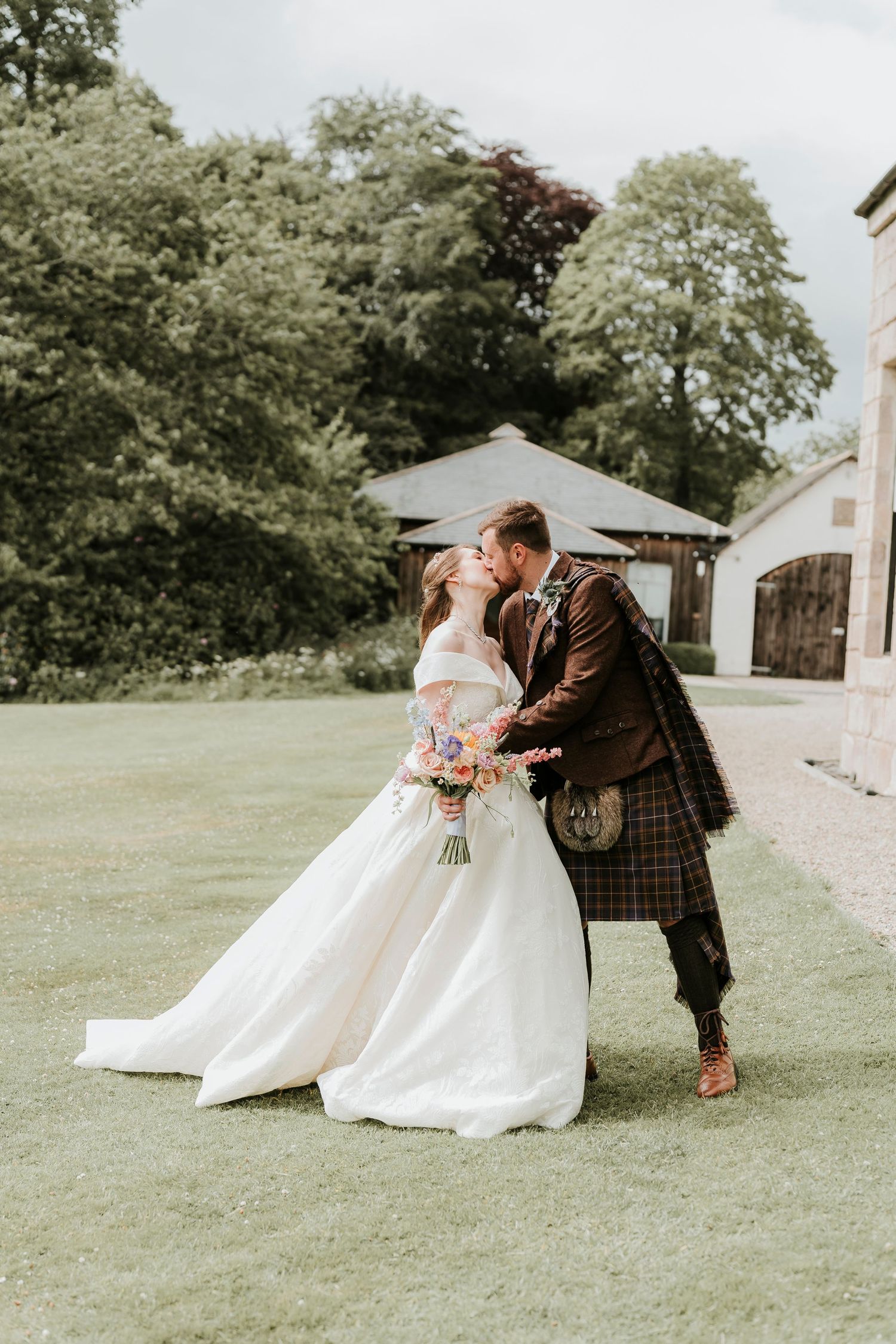 A romantic outdoor wedding photography series showing the bride and groom sharing tender moments on a grassy lawn.