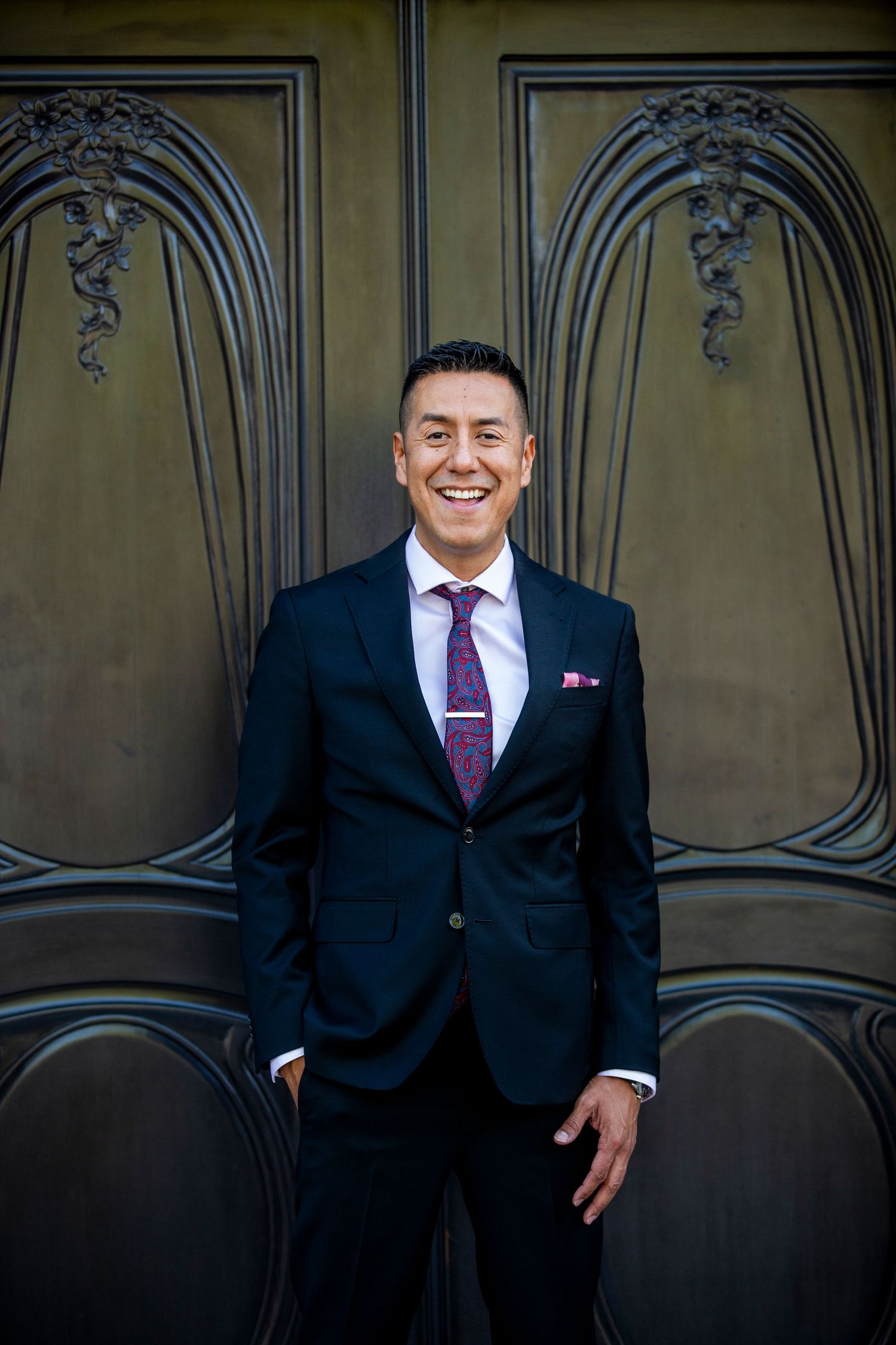 A series of four elegant professional portraits taken against an ornate wall with decorative architectural details and dark seating.