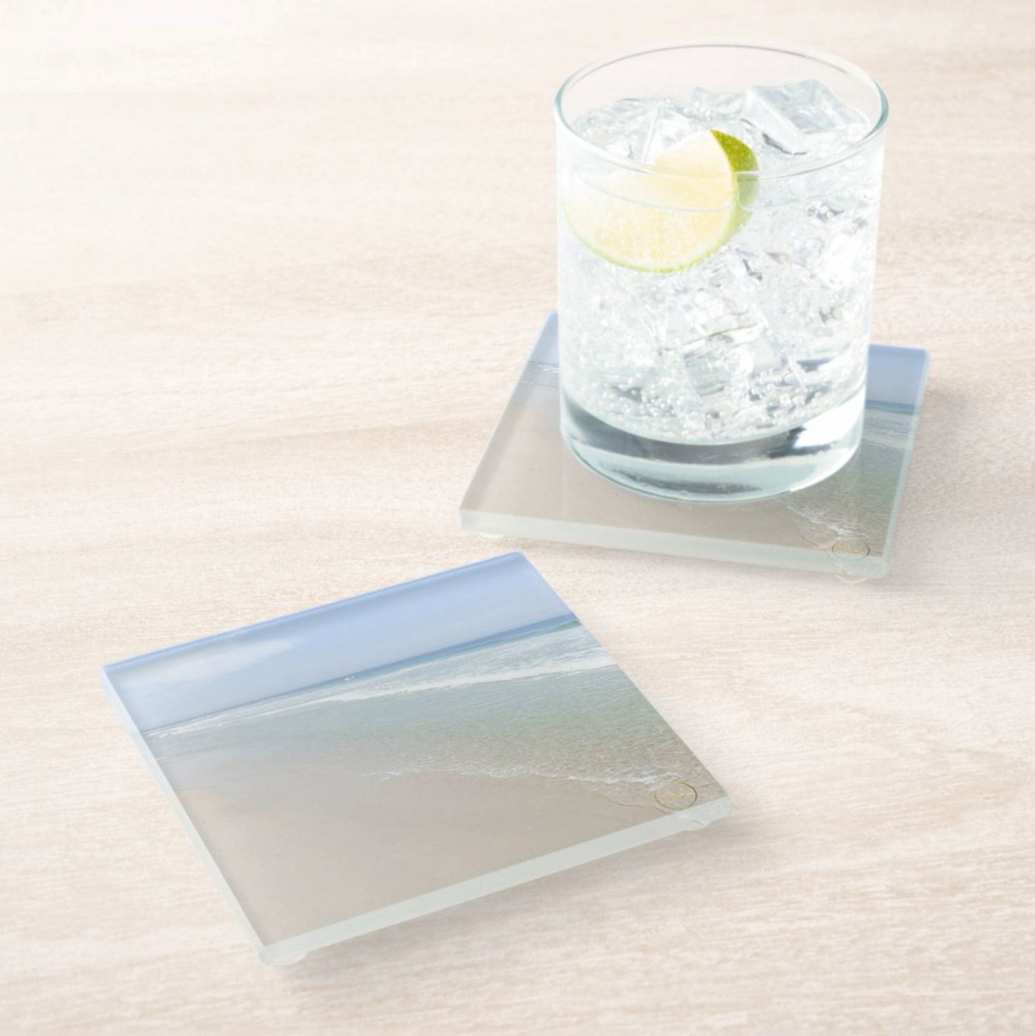 A refreshing gin and tonic cocktail with ice and lemon garnish served in a clear glass on a light wooden surface.