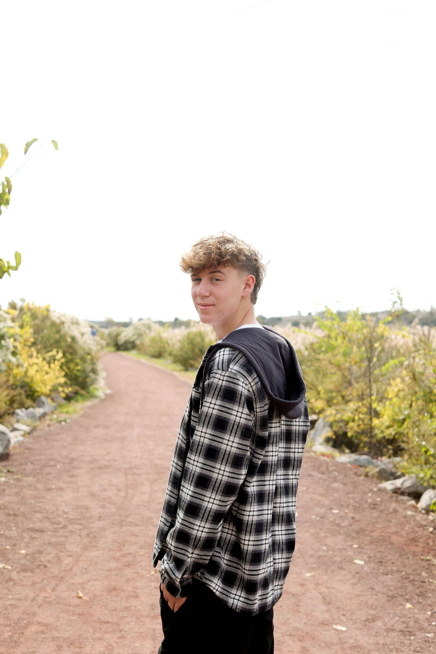 Side view of someone wearing a plaid hoodie jacket on an autumn trail.