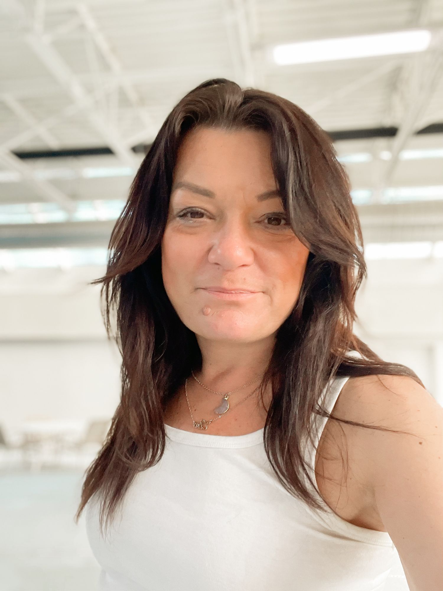 A casual selfie portrait in a bright indoor setting with white walls and ceiling.