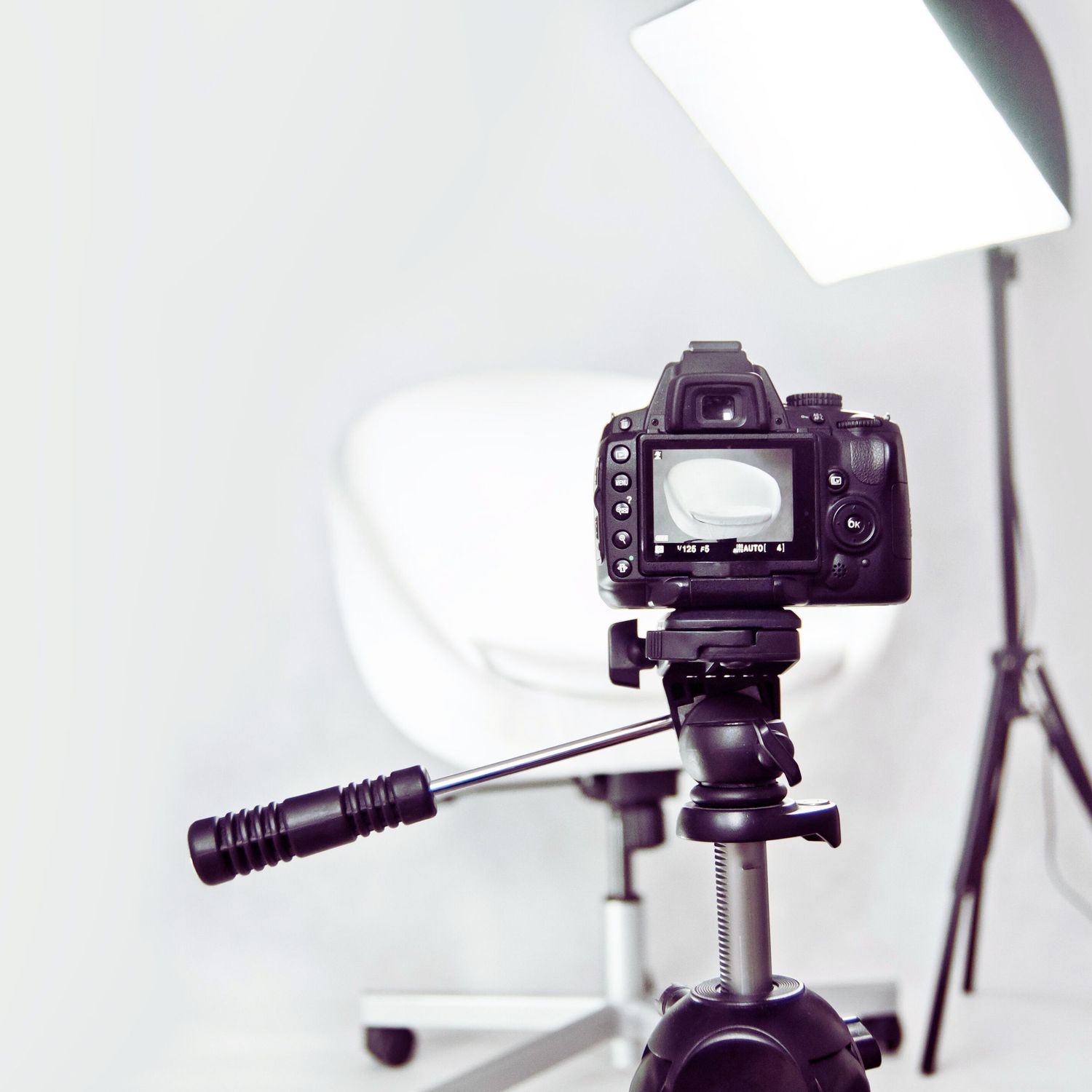 Professional DSLR camera mounted on tripod with lighting equipment visible in studio photography setup.