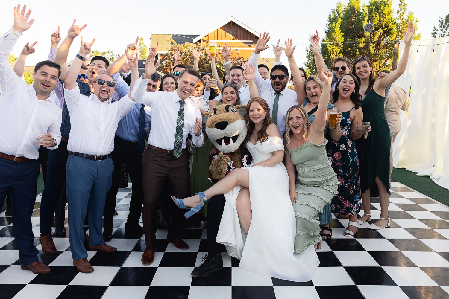 Wedding guests wave goodbye to the newlyweds during their festive celebration on a black and white checkered floor.