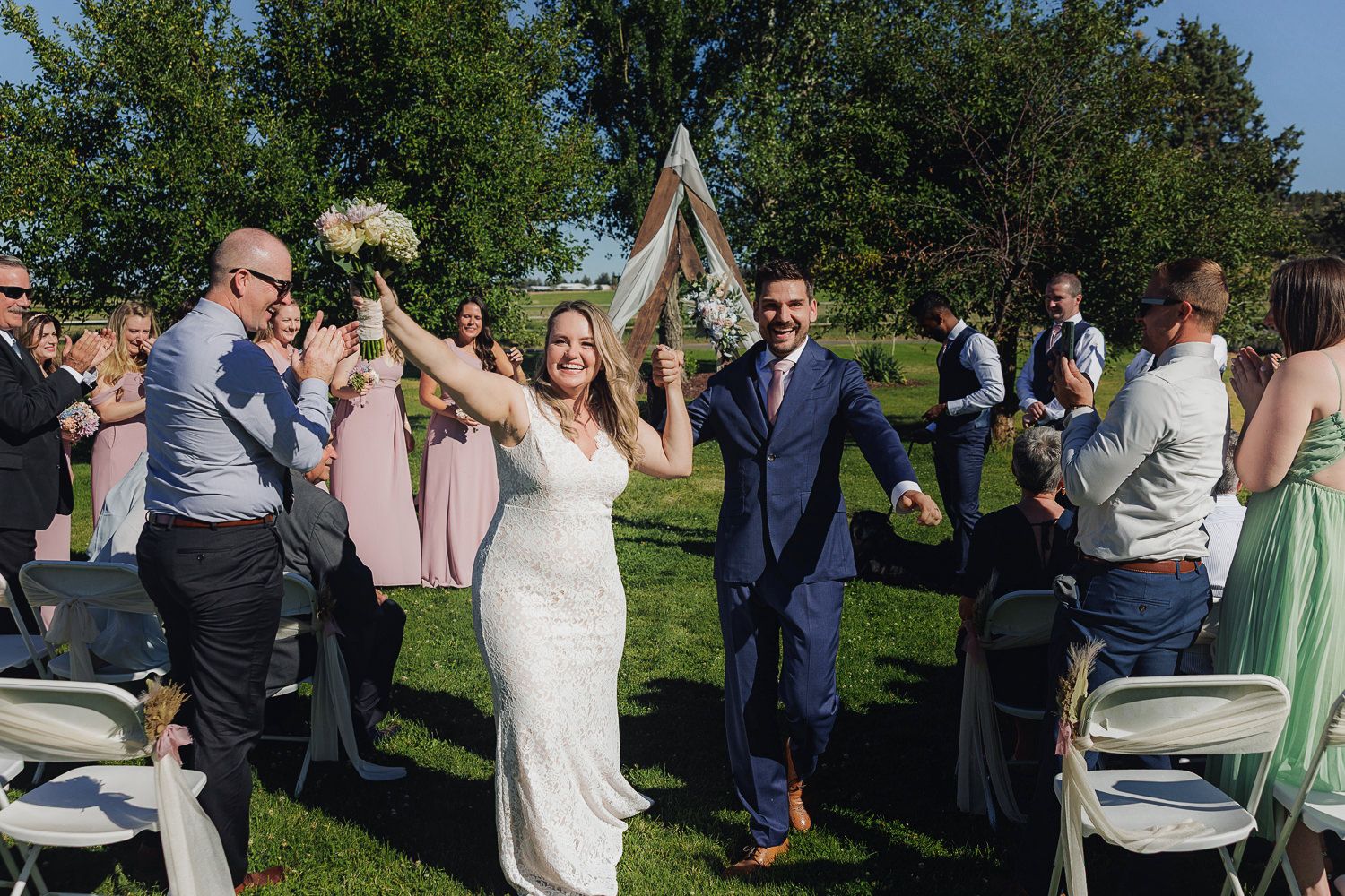 Guests celebrate during an outdoor garden wedding party with soft pastel decor and lush greenery in the background.