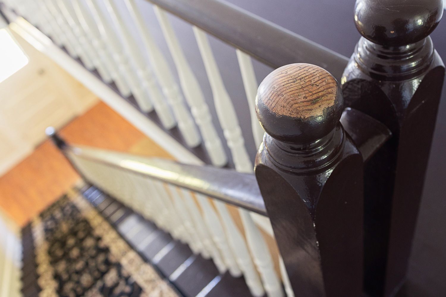 Ornate wooden staircase with dark posts and white painted spindles leading upstairs in interior home setting.