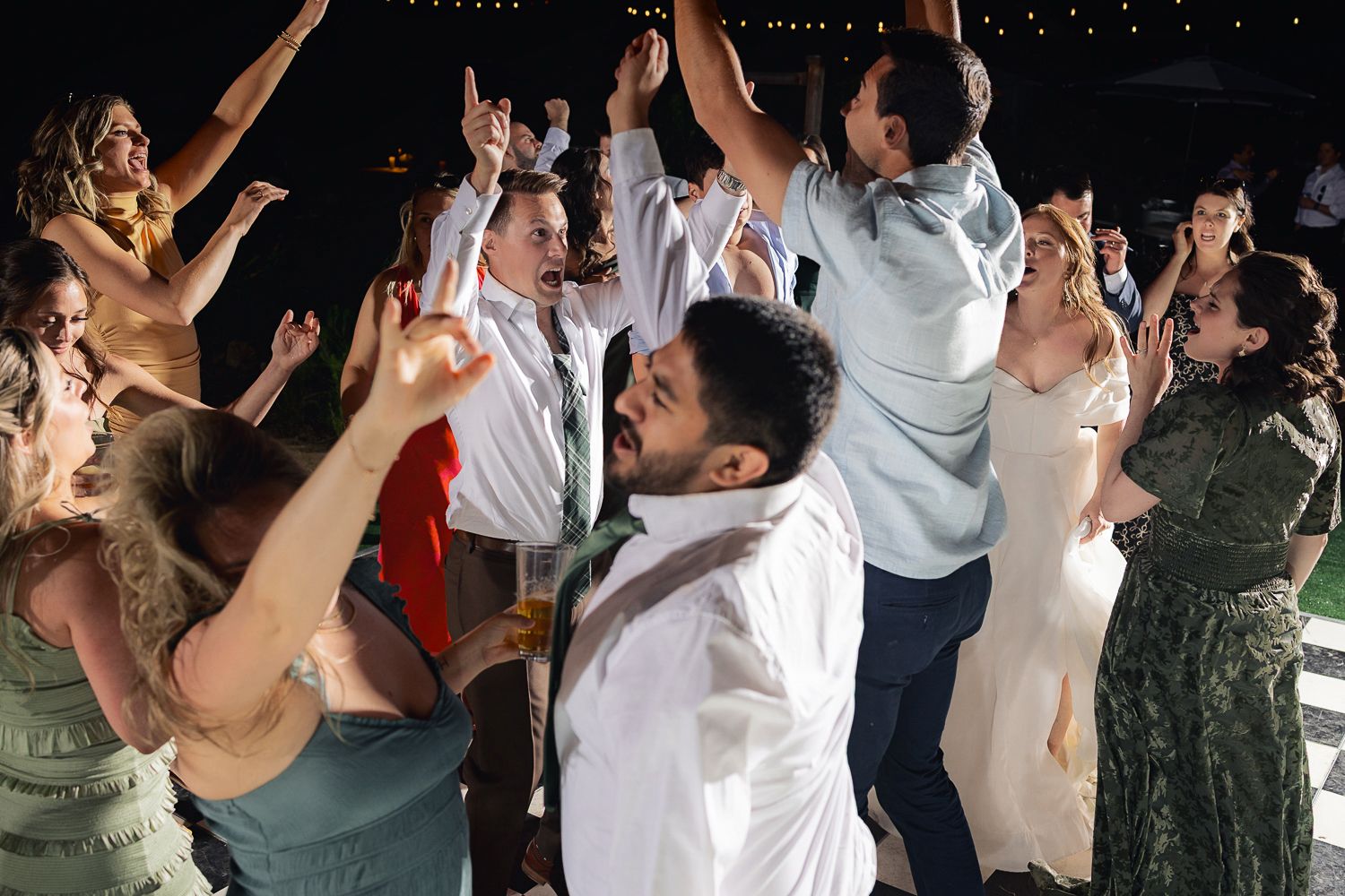 People dancing and enjoying themselves on a crowded dance floor at a wedding reception party.