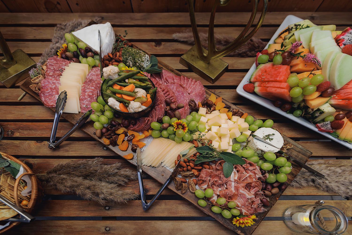 Abundant charcuterie board with meats, cheeses, fruits and nuts arranged on wooden slats.