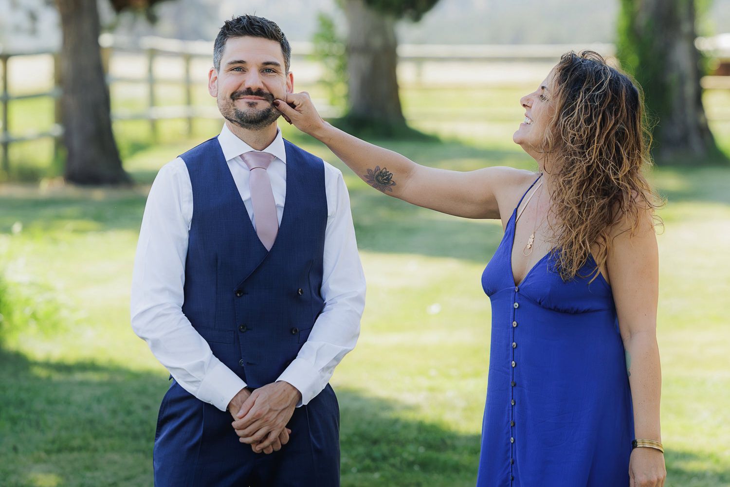 A couple enjoying an outdoor photo session in a park setting wearing coordinated blue and navy formal attire.