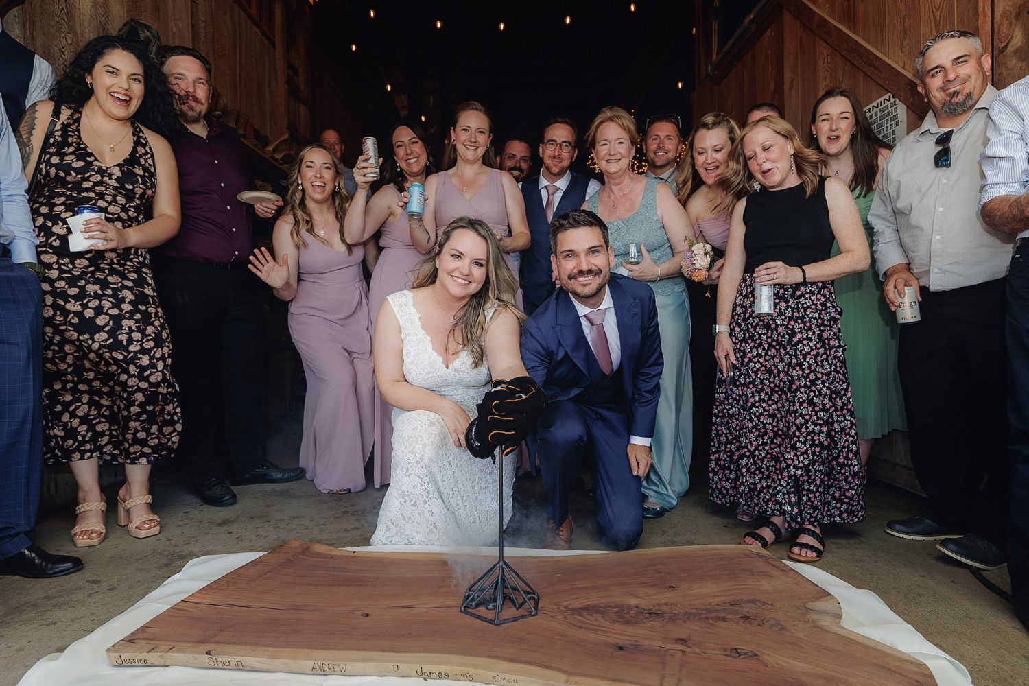 Wedding guests gather on a dance floor for a group photo during the reception celebration.