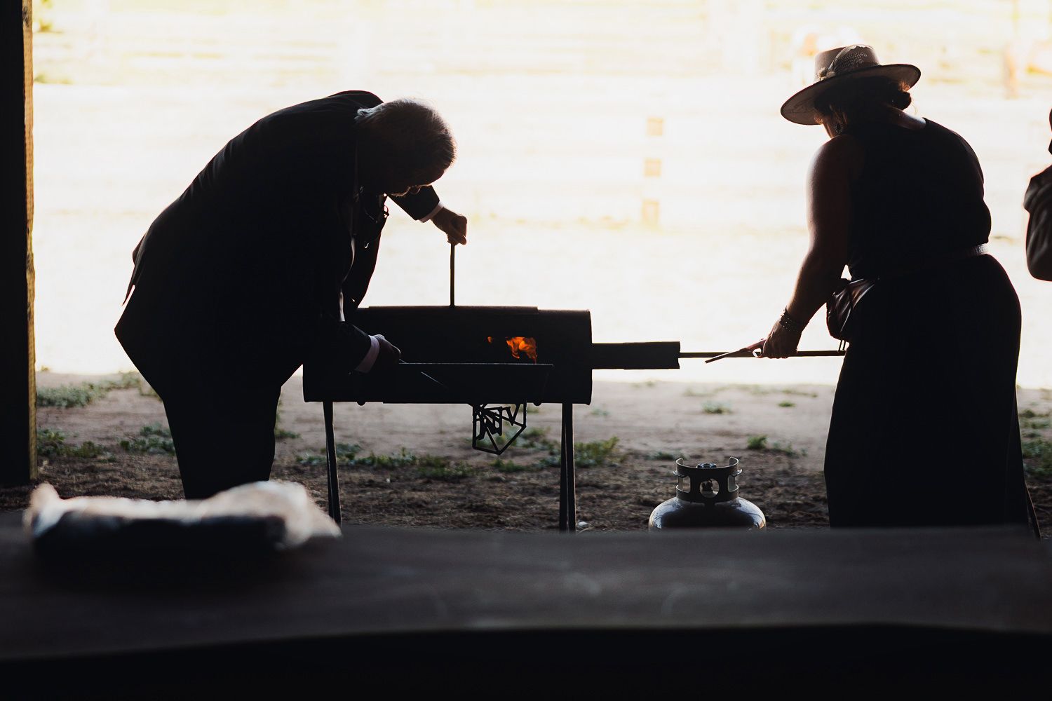 Silhouetted figures working at tables in a dark space create a moody industrial atmosphere.