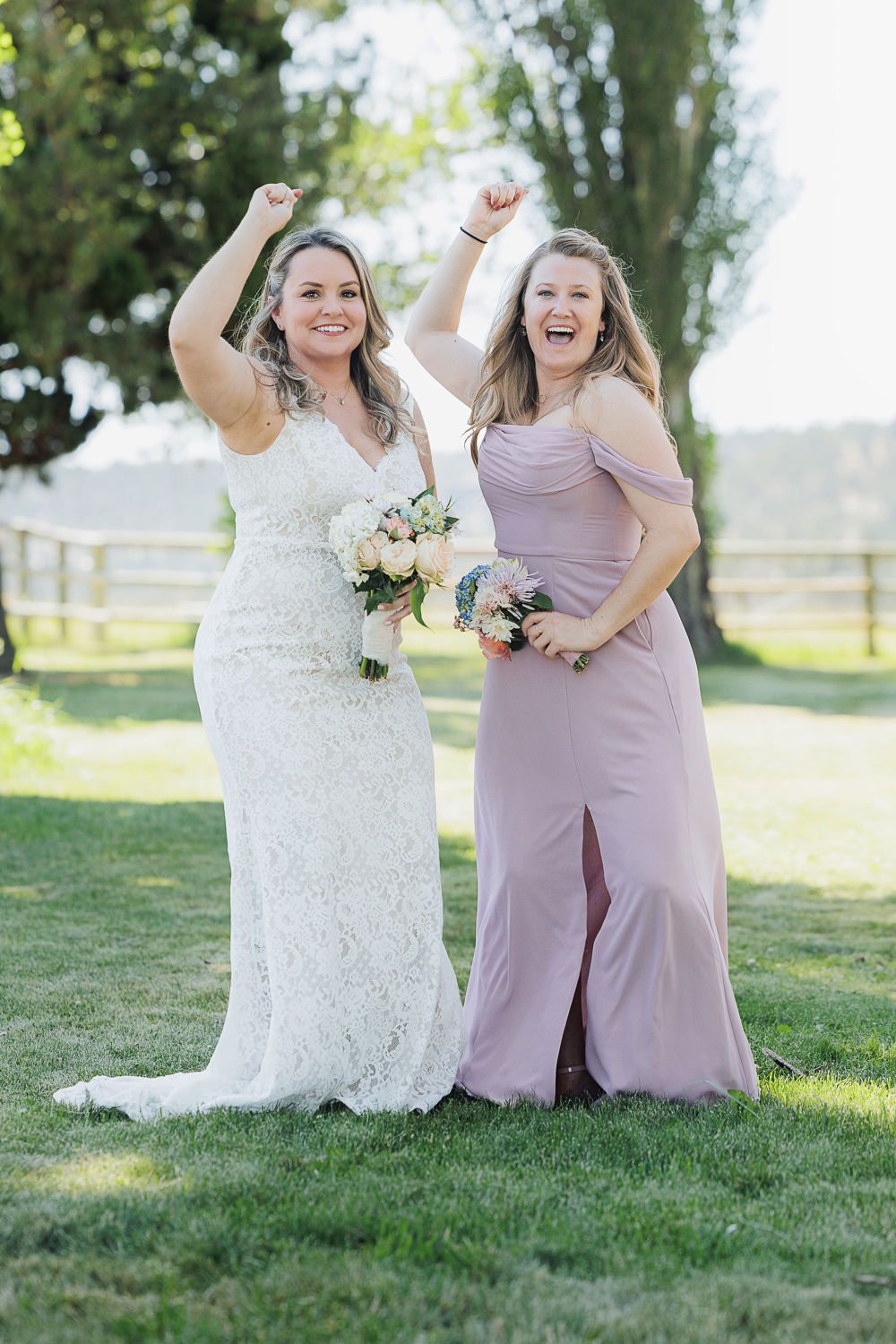 Wedding party in lilac dresses share joyful moments together while posing on green grass during outdoor celebration.