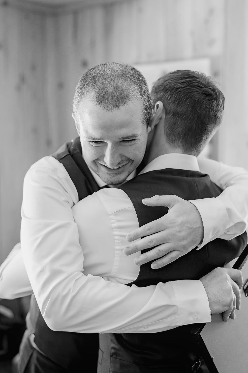 Black and white photo of two people sharing a warm embrace and smile during an emotional moment.