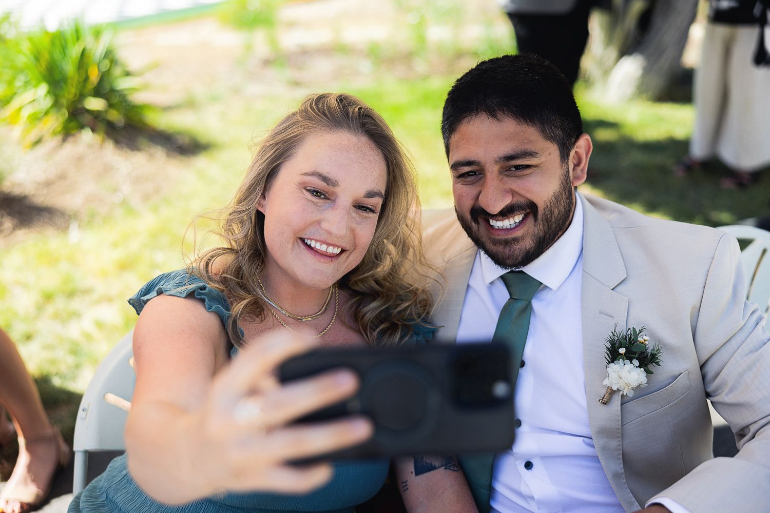 Wedding guests share a joyful moment taking a selfie photo together during an outdoor celebration.
