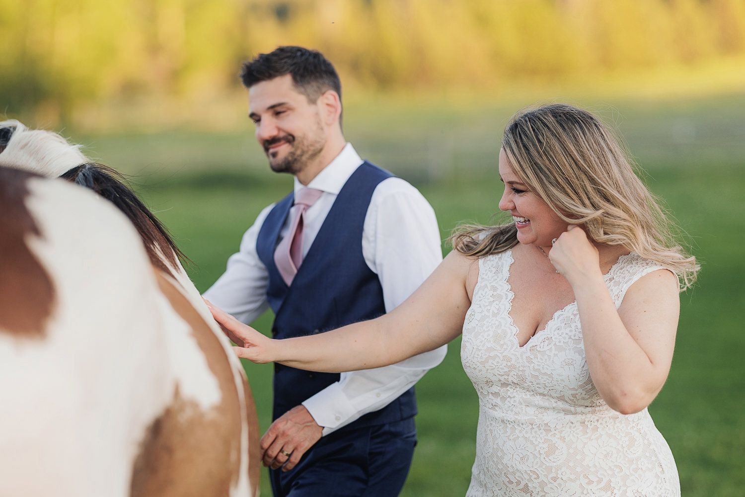 A couple share a joyful moment with their horse during their rustic outdoor wedding celebration.