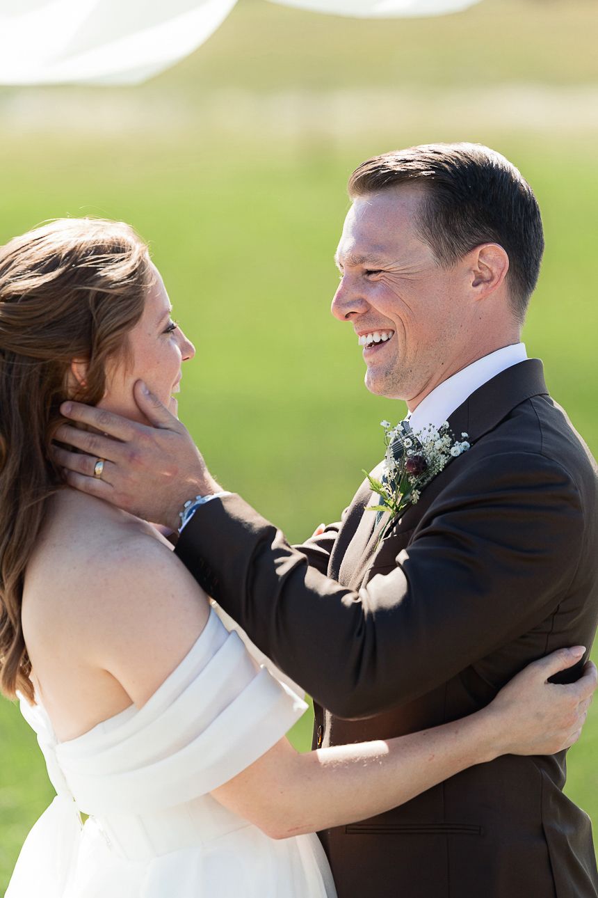 Wedding couple in formal attire sharing an intimate moment of laughter during their outdoor photo session.