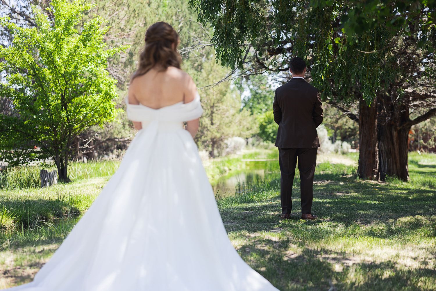 A romantic first look moment between a couple in an outdoor garden setting with lush greenery.