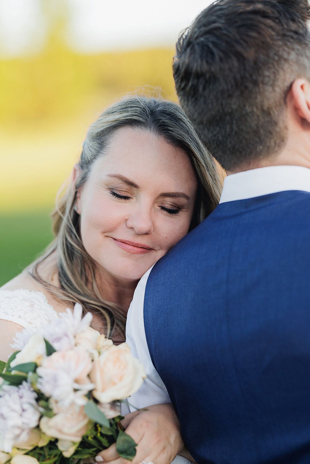 Romantic wedding couple shares intimate moments during sunset photoshoot with peach colored bouquet.