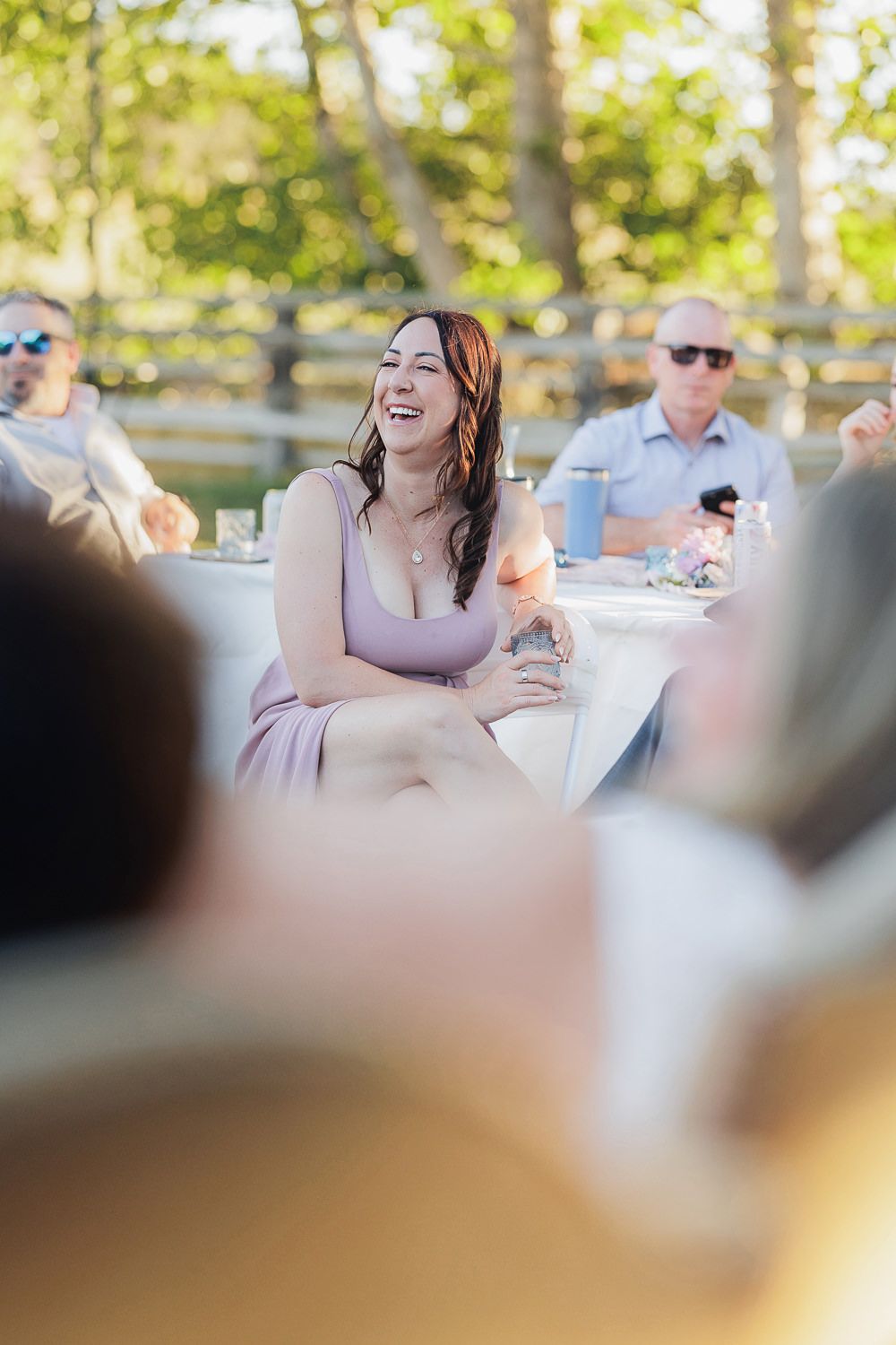 Guests enjoying themselves at an outdoor dinner party with natural bokeh background.